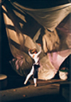 Female dancer facing towards a large swath of billowing white fabric