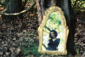 Woman looking into a mirror in the woods